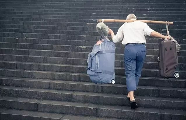 老者扛着行李沿石阶上行